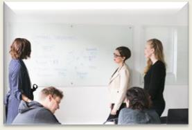 A group of people standing in front of a whiteboard

Description automatically generated